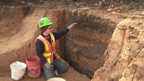  An archaeologist describes the stratigraphy (soil layers) within a mid-1900s privy.