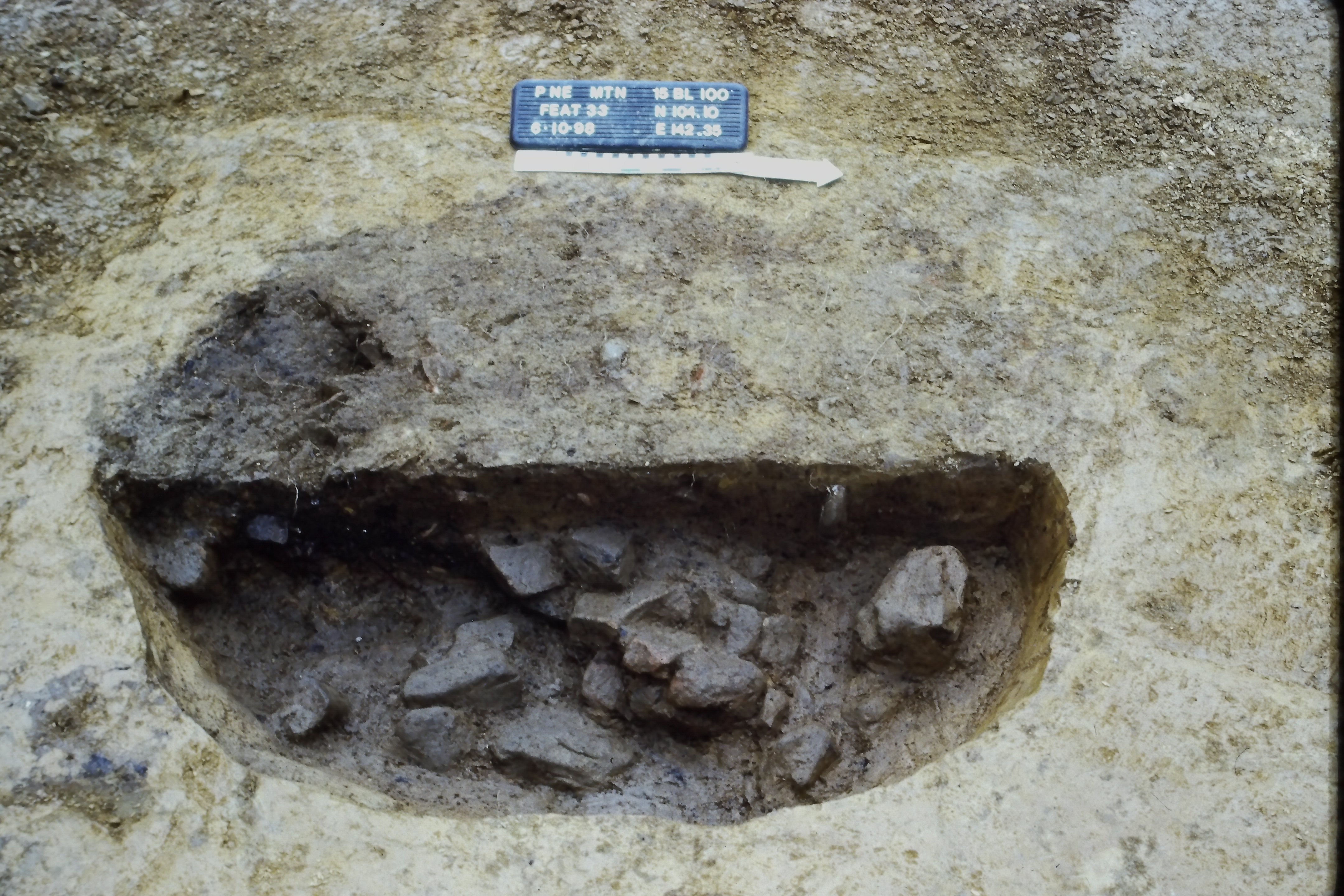 Cooking pit showing burned sandstone rocks after the upper layer of charcoal and ash has been removed.