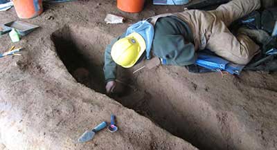 An archaeologist carefully exposes a burial.