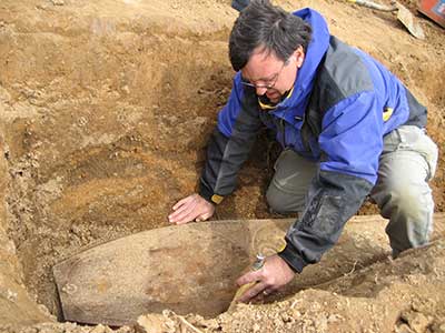 Archaeologist exposes the torpedo-shaped cast-iron coffin.