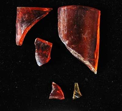 Fragments from a red glass votive prayer candle holder.