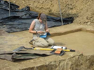 An archaeologist takes notes on soil color and texture.