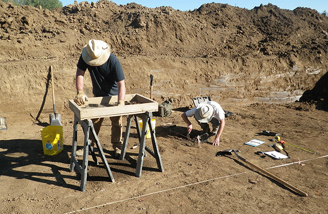 Archaeologists excavate a pit feature.