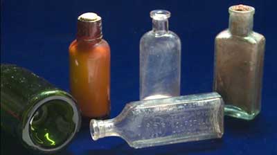 Green glass wine bottle (left) and glass medicinal bottles.